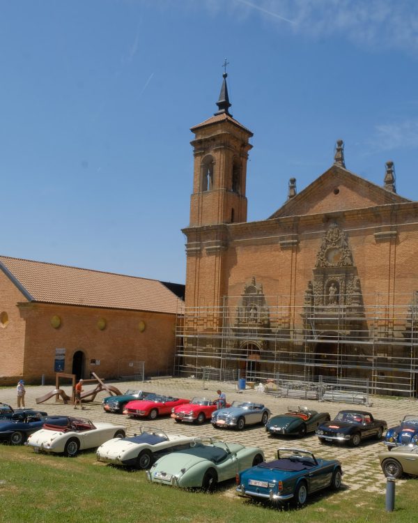 Voitures anciennes devant monument historique pendant rallye des Bastides